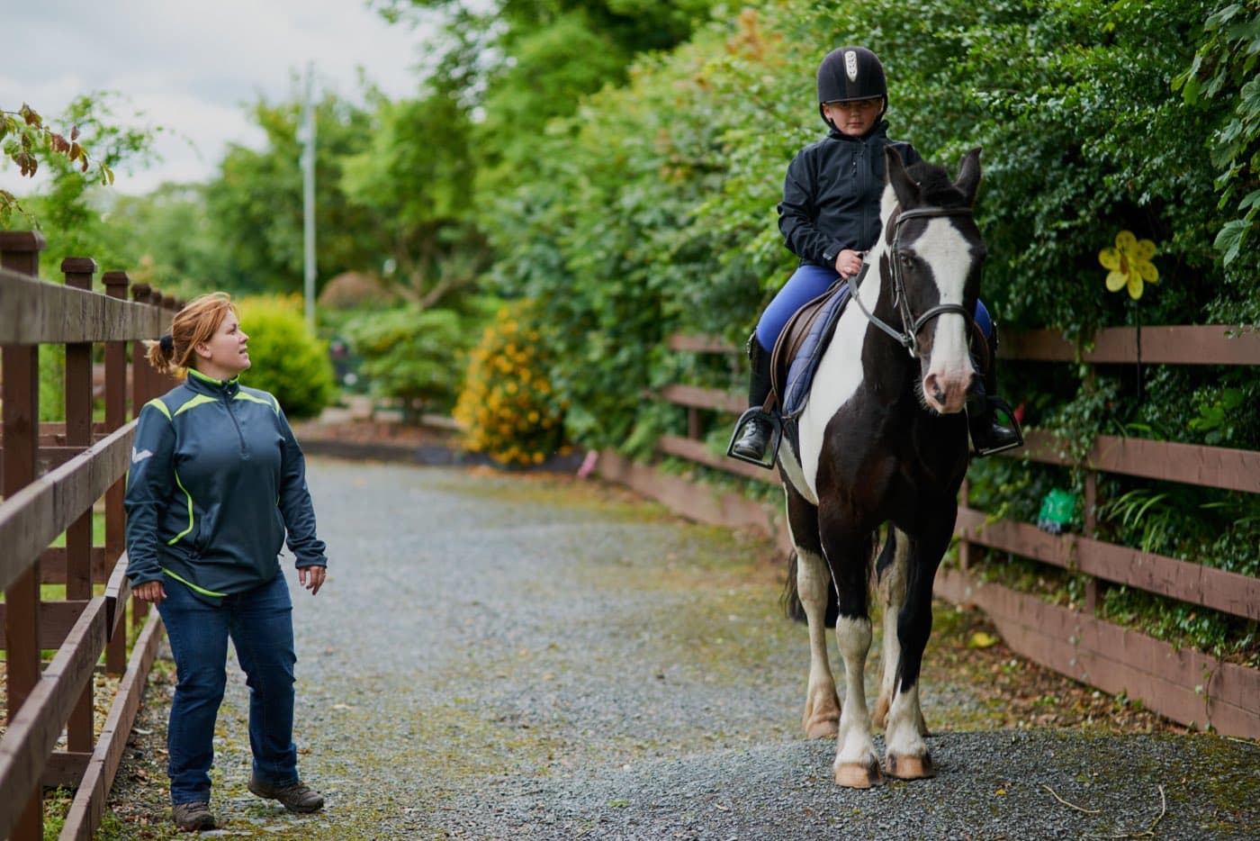 An instructor guiding a young rider along a country path